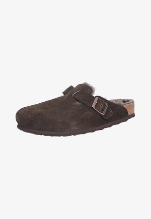 Braune Wildleder-Slipper mit Korksohle, verstellbarem Riemen und weicher Innenauskleidung. Abgerundete Zehenform und strukturiertes Oberflächendetail.