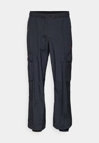 Pantalon cargo noir froissé en nylon avec taille élastique, fermeture frontale à pression et multiples poches à rabat sur les jambes.
