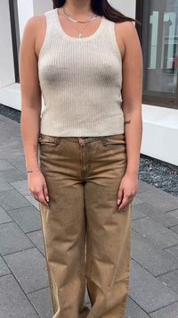 Beige ριμπ τοπ με αμάνικα σχεδίαση, συνδυασμένο με ψηλόμεσο παντελόνι σε άνοιξη απόχρωση και φαρδιά πόδια, και τα δύο κατασκευασμένα από μαλακό ύφασμα.