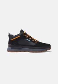 Basket noire mi-montante avec lacets orange, semelle grise et brune, et logo Timberland sur le côté, vue de l'extérieur.