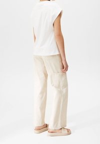 Witte top met korte mouwen gekoppeld aan beige wijde broek met zijzakken. Een eenvoudig ontwerp met een comfortabele pasvorm en een zachte textuur.