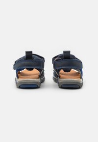 Navy blå sportsandaler med justerbare stropper, mesh- og lædermaterialer, med en polstret sål og tekstureret gummisål.