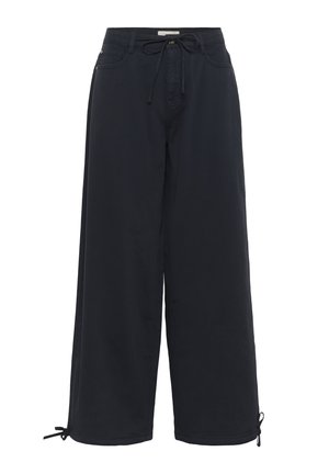 Melnas platās bikses, kas izgatavotas no mīksta auduma, ar aukliņu jostu un regulējamiem saišu elementiem pie potītēm, lai nodrošinātu pielāgojamu fit.