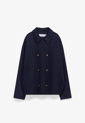 Donkerblauwe wollen peacoat met een ronde kraag, dubbelzijdige messing knopen, verlaagde schouders en zijzakken. Gladde textuur, losse pasvorm.