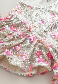 Sidabrinis blizgučių audinys su rožinėmis ir purpurinėmis gėlių akcentais, turintis švelnią tekstūrą ir raukinį dizaino elementuose.