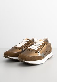 Braune Sneakers aus Wildleder und synthetischen Materialien, mit einem eleganten Design, weißen Schnürsenkeln und metallischen Akzenten an den Seiten.
