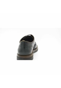 Chaussure en cuir noir avec un bout arrondi, perforations brogue détaillées, une finition lisse et une semelle marron robuste. La vue de derrière met en valeur le design.