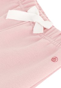Pantaloni shorts in tessuto rosa con vita elastica e dettaglio di un fiocco bianco. Presentano un piccolo logo in una tonalità contrastante.
