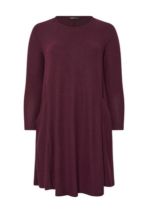 Vestido largo burdeos de manga larga hecho de una tela suave. Presenta un escote redondo y bolsillos laterales. Tiene una forma acampanada con un corte holgado.