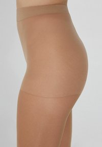 Tights transparent beiges que presentan una textura suave y elástica, con una cintura alta, diseñadas para un ajuste ceñido y un uso cómodo.