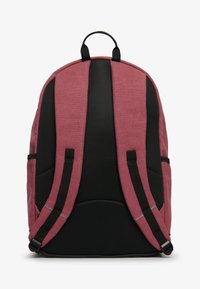 Mochila roja y negra con tejido texturizado, respaldo acolchado, correas de malla y bolsillos laterales; cuenta con costuras reforzadas y un lazo para colgar.