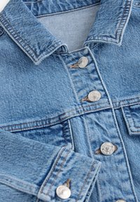 Modrá rifľová bunda s golierom, kovovými gombíkmi, viditeľným šitím a rukávom so zapínaním na gombík.