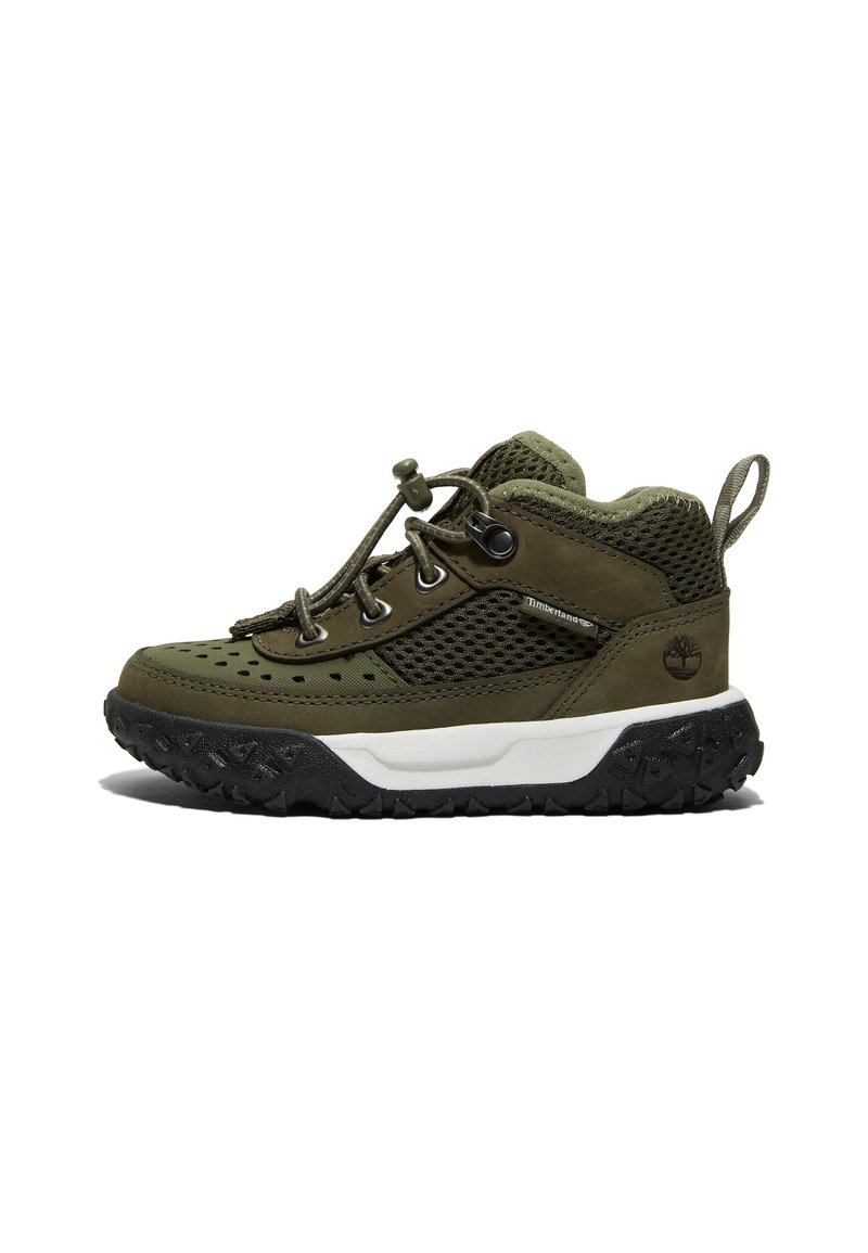 Chaussure en maille verte et cuir avec une semelle en caoutchouc noir texturé, des lacets élastiques et une languette au talon. Présente un logo sur le côté.