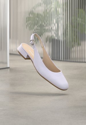 Witte slingback schoen met een lage blokhak, gladde, leerachtige textuur, afgeronde neus en verstelbare enkelriem.