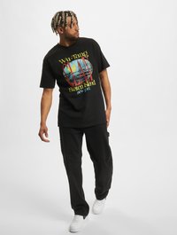 Sort t-shirt med farverig "Wu-Tang Clan Staten Island" grafik, parret med sorte bukser og hvide sneakers. Casual pasform og bomulds materiale.