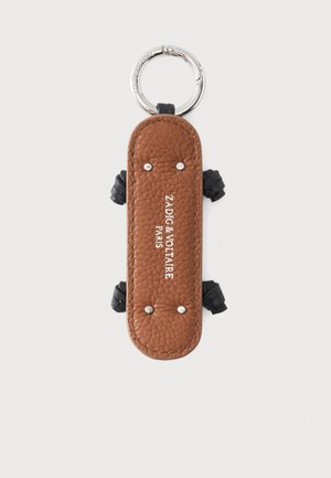 Porte-clés en cuir marron texturé avec rivets argentés et détails noués noirs, marqué Zadig & Voltaire Paris en texte blanc.