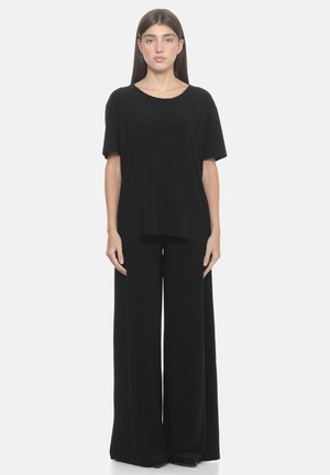 Top nero con scollo rotondo, maniche corte e vestibilità ampia abbinato a pantaloni neri a gamba larga, entrambi realizzati in tessuto morbido.