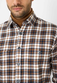 Camicia a quadri con colori bianco, marrone e blu navy, dotata di colletto button-down, bottoni blu e taschino sul petto. Tessuto morbido.
