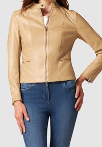 Beige leren jas met een opstaande kraag, ritssluiting aan de voorkant, twee zijzakken en een aansluitend ontwerp; gladde textuur met subtiele naaddetails.