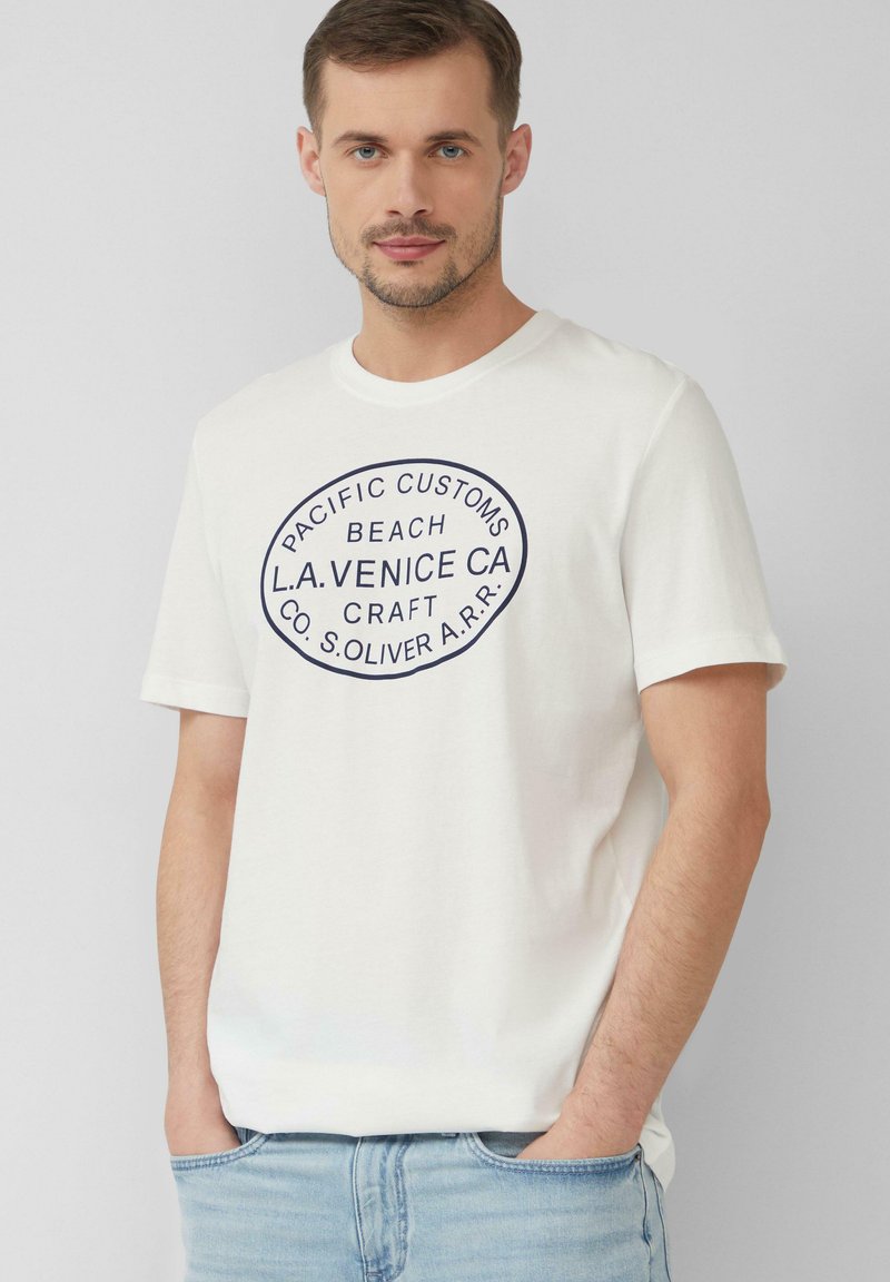 Witte katoenen t-shirt met een cirkelvormige marineblauwe grafiek waarin de tekst "PACIFIC CUSTOMS BEACH L.A. VENICE CA" staat. Korte mouwen, ronde hals.