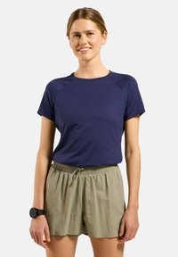 Marineblauwe top met korte mouwen en raglanmouwen, gecombineerd met lichtgroene shorts met trekkoord en een elastische tailleband van zachte stof.