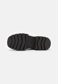 Talpa de cauciuc neagră cu un model de tread în zigzag, prezentând caneluri adânci pentru tracțiune și stabilitate. Suprafață netedă în jurul tread-ului.