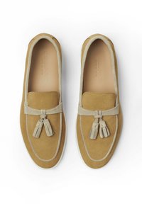 Mocassini in suede color sabbia con dettagli in suede grigio, punta arrotondata, frange decorative e suola in gomma bianca. Logo impresso sulla soletta.