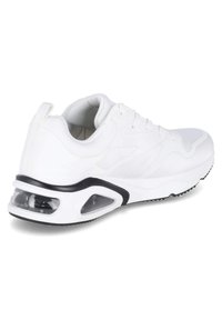 Zapatilla deportiva blanca con un upper texturizado, cierre de cordones y una unidad de amortiguación de aire transparente en la suela. Presenta un acento negro alrededor del talón.