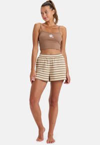 Bruine geribbelde cropped tanktop met bloemenborduurwerk, gecombineerd met beige gestreepte shorts met een elastieken tailleband en zijzakken.