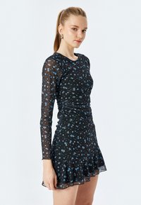 Schwarzes Kleid mit langen, transparenten Ärmeln, gerafftem Körper, ausgestelltem Saum und blauen Blumenmustern. Leichtes, strukturiertes Gewebe.