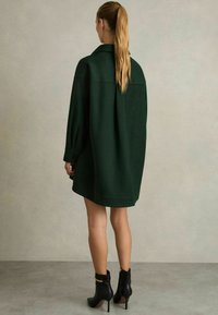 Roheline villasegune oversized särgimek uniformi krae ja pikkade varrukatega. Kombineeritud mustade pahkluu saapadega, millel on kuldsed aksessuaarid.
