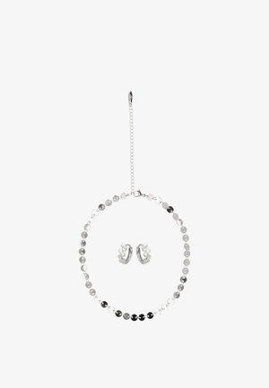 Ezüstszínű ékszerszett, amely kör alakú nyakláncot tartalmaz váltakozóan fényes és matt korongokkal, valamint hozzáillő fülbevalókat, amelyek fürtök formájában vannak kialakítva.
