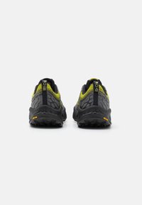 Sorte og grå trail-sko med en tekstureret mesh-overdel, klare gule accenter og en Vibram sål, der har et robust design til godt greb.