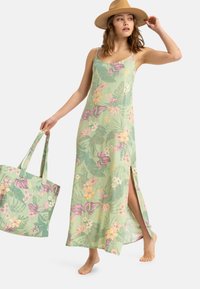 Abito maxi floreale in tessuto verde chiaro con spacco laterale, caratterizzato da stampe tropicali in rosa e giallo. Accompagnato da una borsa a tracolla coordinata.