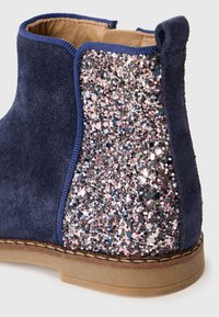 Marineblauer Wildleder-Ankle Boot mit einem glitzernden Glitzerpaneel in Rosa- und Silbertönen, einer strukturierten Oberfläche und einer braunen Sohle.