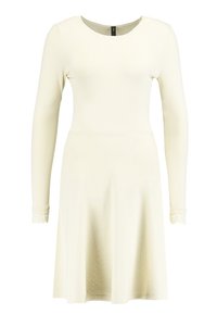 Långärmad klänning i krämfärg, tillverkad av mjukt tyg. Har en rund halsringning och spetsdetaljer vid ärmsluten. A-linjekjol.