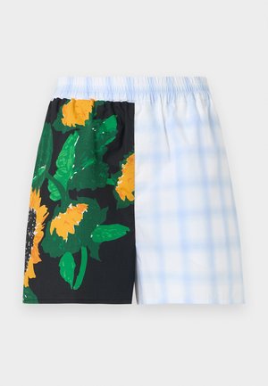 Σορτς με ελαστική μέση και στυλ με διαχωρισμό: η μία πλευρά μαύρη με μεγάλα κίτρινα ηλιοτρόπια και πράσινα φύλλα, η άλλη πλευρά ανοιχτό μπλε με λευκό καρό μοτίβο.