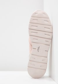 Světlé růžové sportovní boty s texturovaným svrškem, perforacemi pro prodyšnost a bílou gumovou podešví s výraznými vzorci vzorku.