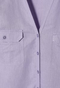 Lichtpaarse linnen shirt met een V-hals, twee borstzakken en knoopsluiting. Gestructureerde stof met zichtbare stiksels en knopen.