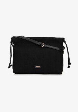 Black fabric crossbody bag with a textured surface, adjustable faux leather strap, drawstring closure, and a small front logo plate.