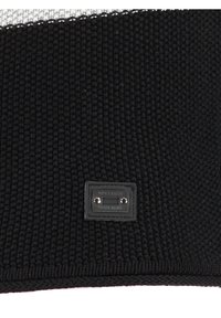 Schwarzer, gestrickter Stoff mit einer strukturierten Oberfläche, ausgestattet mit einem silbernen Etikett, auf dem der eingravierte Text "KEY LARGO TRADE MARK" zu sehen ist.