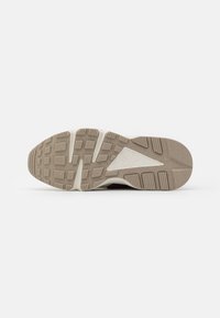 Semelle beige et blanche à motifs d'une chaussure Nike Air avec une accroche texturée et le logo Nike Air dans le triangle central.