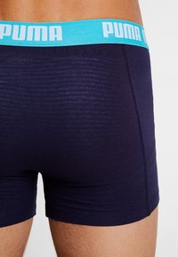 Navy blue boxer shorts with a light blue Puma logo waistband, made of smooth fabric, featuring a snug fit and subtle texture detail.