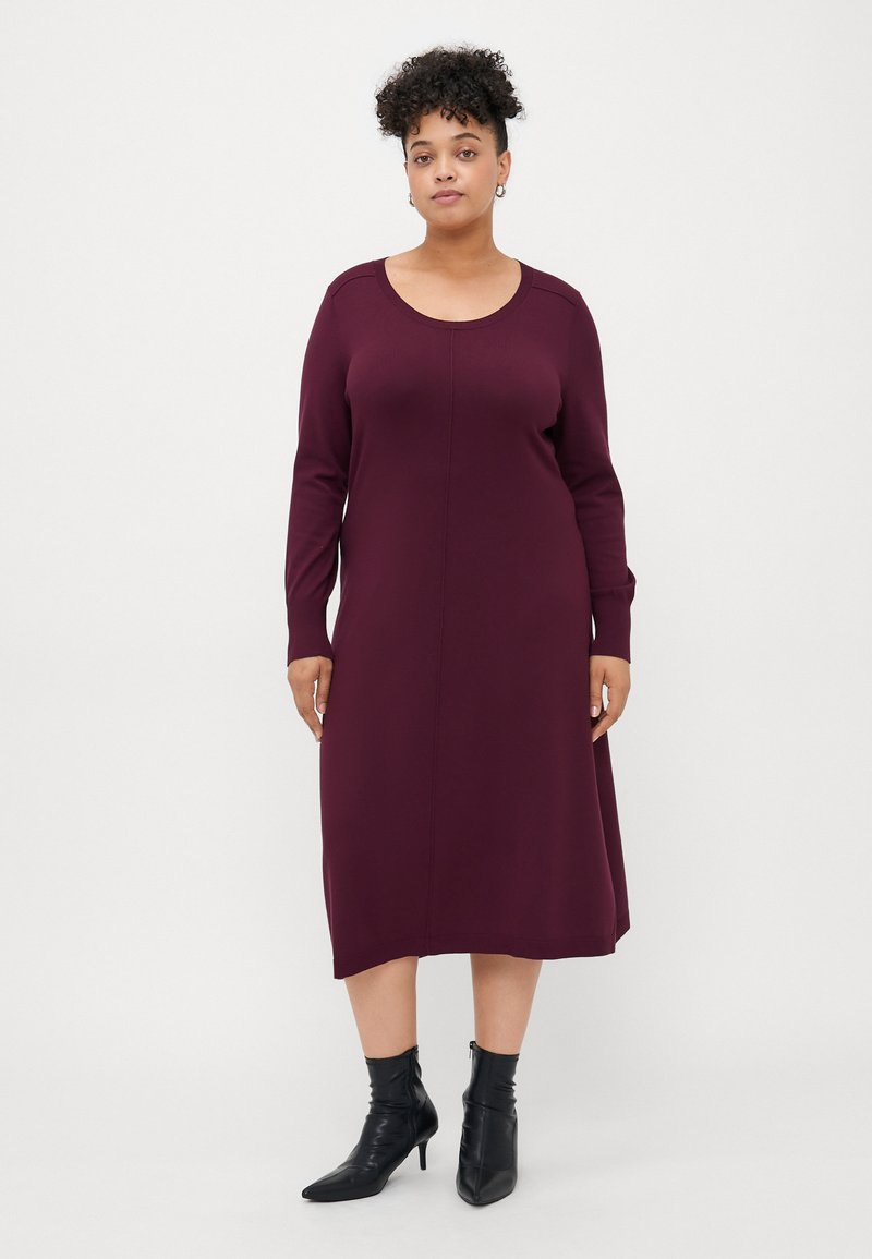 Burgundy long-sleeve dress with a round neckline and a straight cut. Smooth fabric, mid-calf length, paired with black ankle boots.