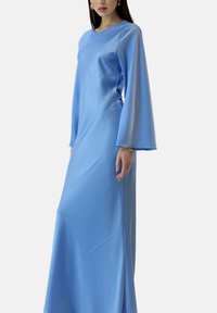 Jurk met lange mouwen tot op de vloer van lichtblauwe satijn, met een gladde textuur en een losse pasvorm met wijde mouwen en een zijsplitsing.