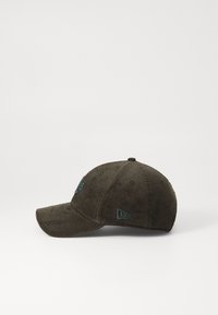 Olive green corduroy cap with a curved brim, featuring embroidered teal accents on the front and side. Textured surface detail noted.