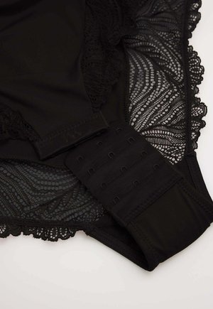 SSujetador de encaje negro con bordes ondulados y cierre de gancho y ojo sobre un fondo claro.