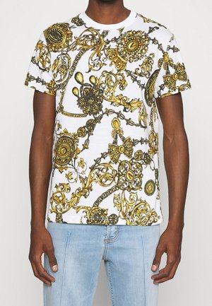 Biały t-shirt z krótkim rękawem z misternym, złoto-czarnym wzorem barokowym, zawierającym różnorodne elementy dekoracyjne i zdobienia.