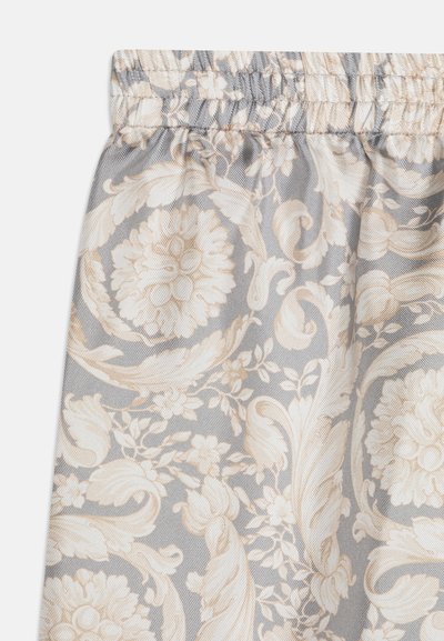 Floral-patterned fabric featuring intricate beige and soft cream blooms on a light gray background with a gathered elastic waistband texture.
