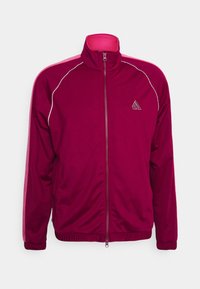 Bordeaux färgad träningsjacka med hög krage, full frontdragkedja, vita detaljer och ribbade muddar. Strukturerad tyg med logga på vänster bröst.